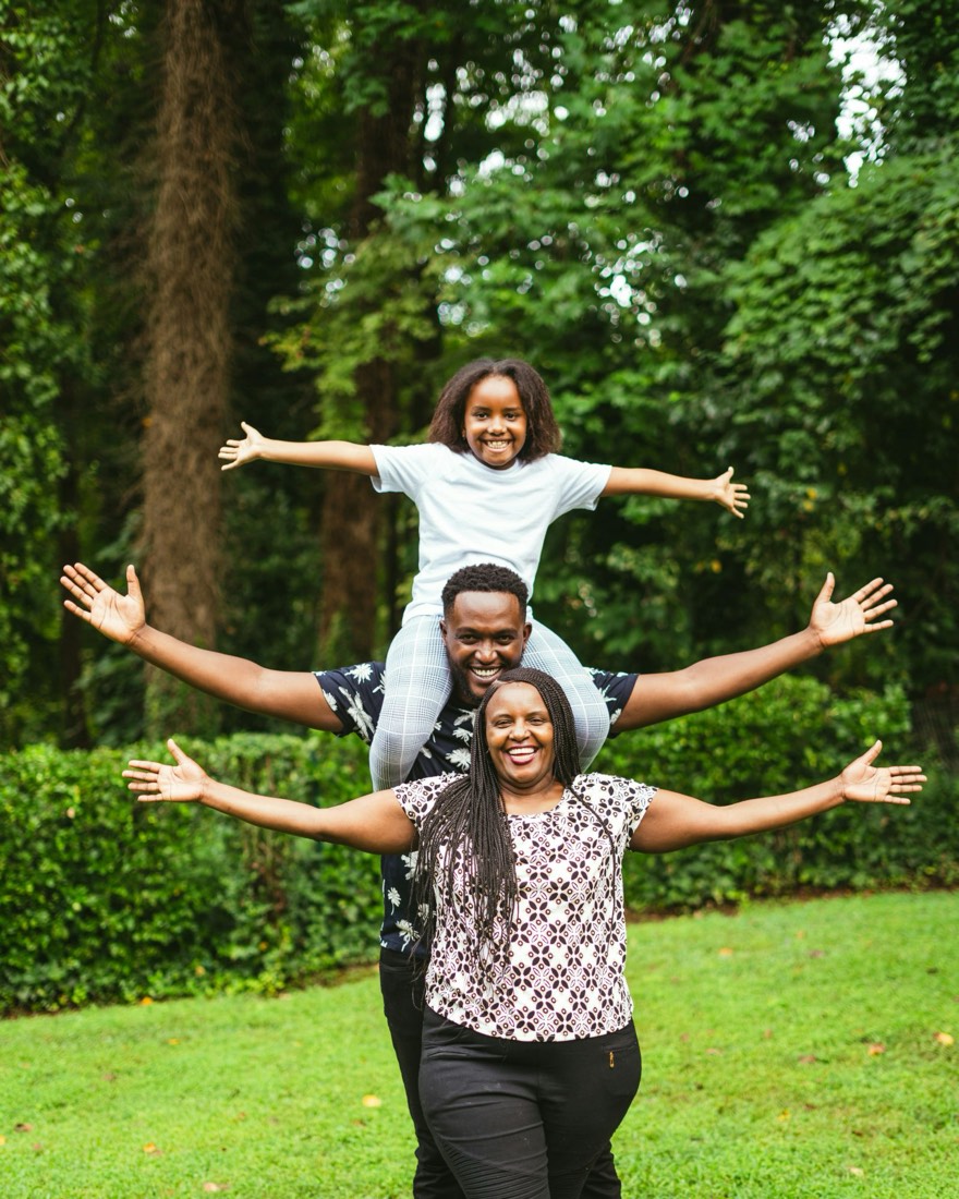 A smiling family of three with their arms spread wide